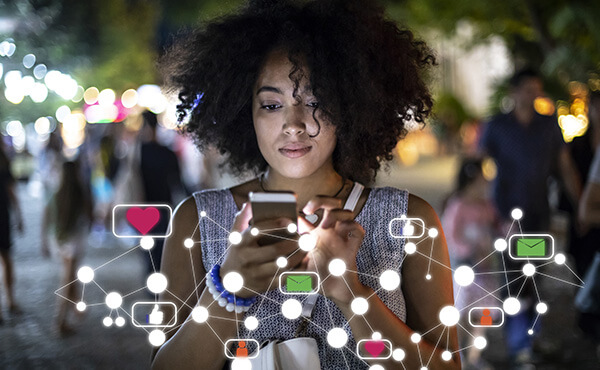 A woman with curly hair smiling while holding a smartphone