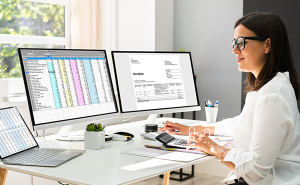 A woman sitting at a desk with two computer screens