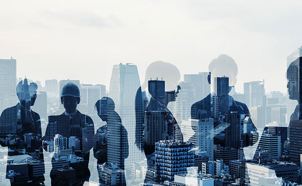 Silhouettes of people standing in front of a city skyline at sunset